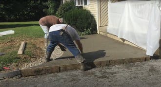 Two men finishing concrete slab.