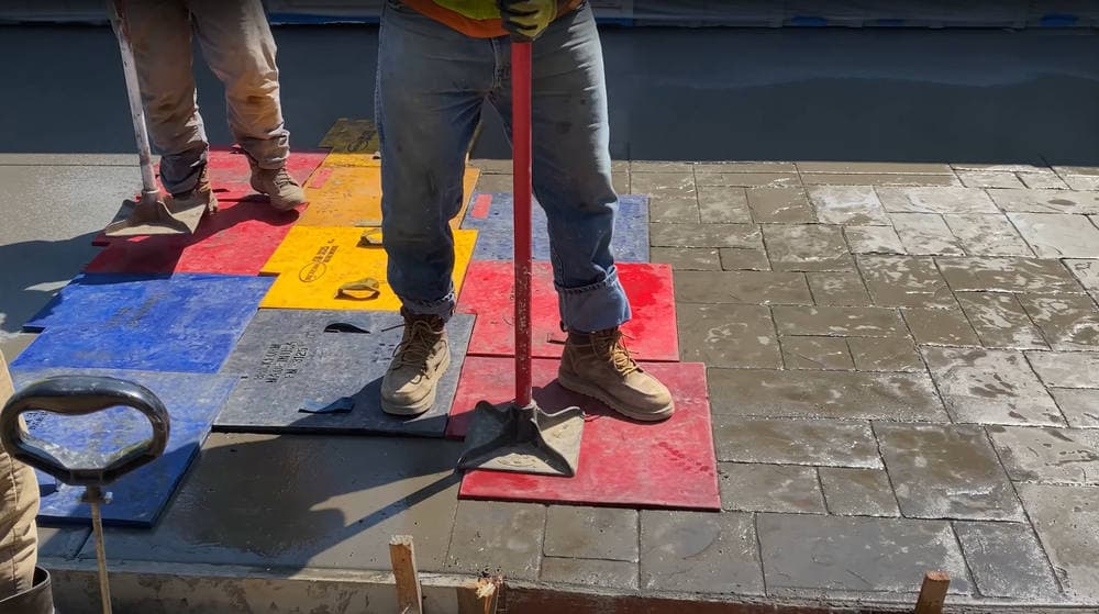 Crew stamping concrete in patio.