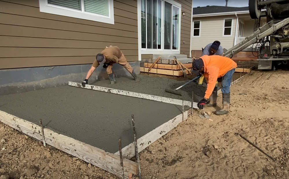 Crew working on laying concrete for patio.